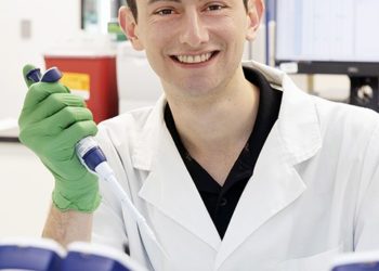 Smiling Man Working In Laboratory Wearing Lab Coat