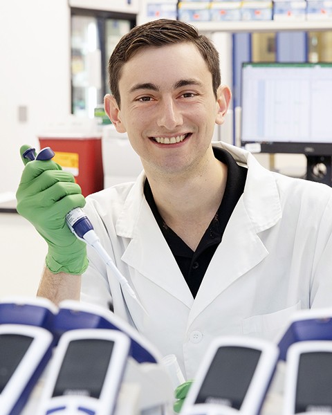 smiling man working in laboratory wearing lab coat