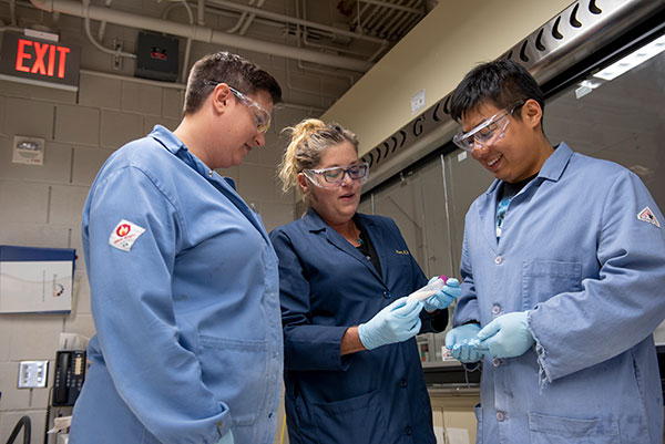 instructor showing two students a vile in laboratory