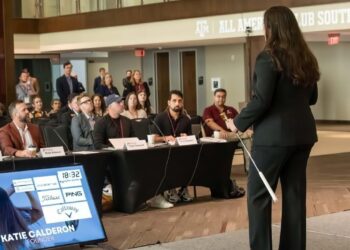 woman holding a golf club on stage looking out into a audience of people