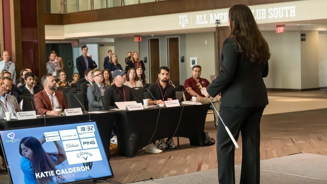 woman holding a golf club on stage looking out into a audience of people