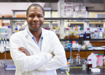 A man in a white lab coat standing in a laboratory