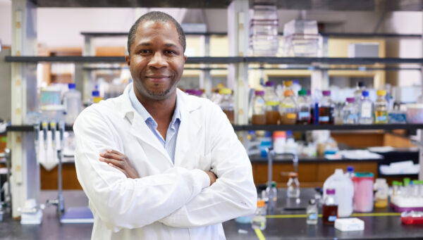 A man in a white lab coat standing in a laboratory