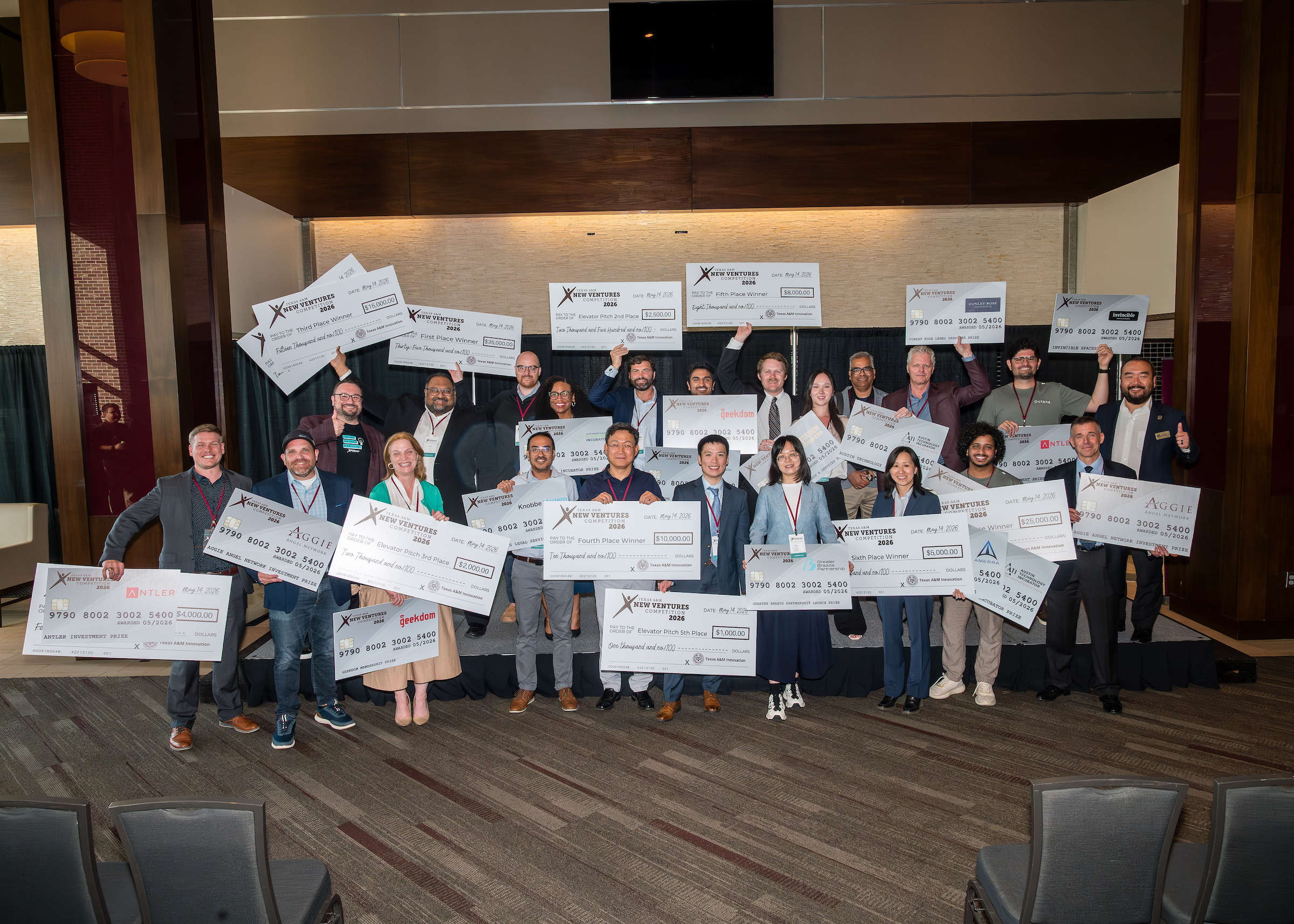 A group of people standing and holding large checks